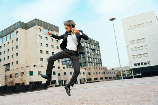 Young entrepreneur jumping and dancing to celebrate his successful day at work. Concept about freedom and carefree in business career