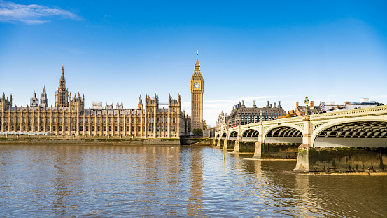 View across River Thames to Palace of Westminster and Elizabeth Tower in Gothic Revival style and 19th-century arch bridge linking Westminster and Lambeth.