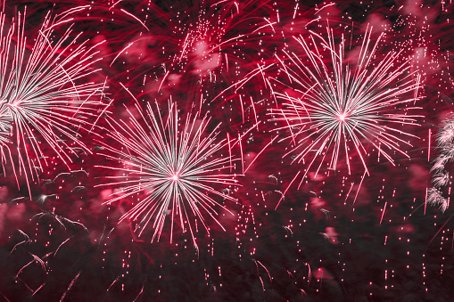 Holiday fireworks with sparks, bright nebula, smoke on black sky. Festive holiday background, burgundy magenta color