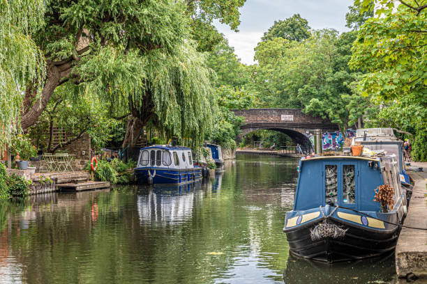 Houseboats on the Regent's Canal in London Ruhig im Wasser liegende Hausboote mit viel Natur auf dem Regent’s Canal im Londoner Stadtteil Camden regents canal stock pictures, royalty-free photos & images