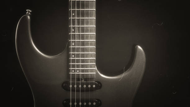 istock A vintage electric guitar standing upright with textured noir concept as black silver wallpaper. Music concept 1446488607