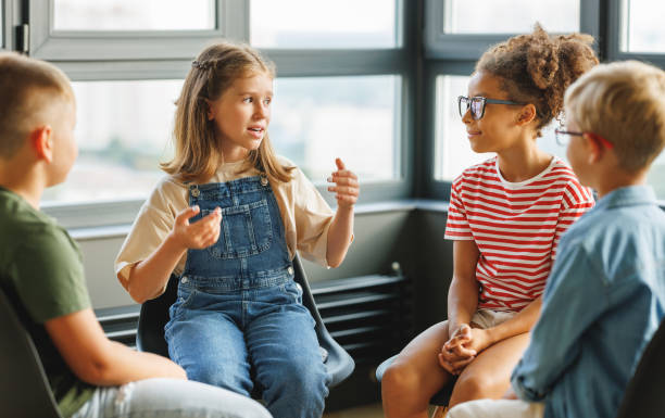 praca grupowa dzieci w wieku szkolnym, uczniowie omawiają wspólny projekt w szkole - childhood zdjęcia i obrazy z banku zdjęć