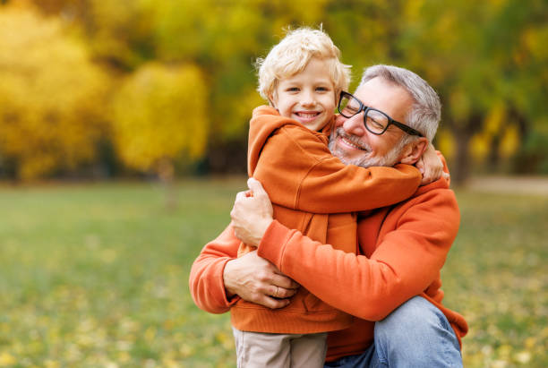 happy grandfather and grandson hug on autumn walk in park happy family smiling grandfather and grandson hug on autumn walk in park grandparent stock pictures, royalty-free photos & images