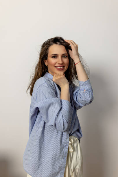 istock A smiling fashion model is standing in front of a white wall in a studio. 1446489963