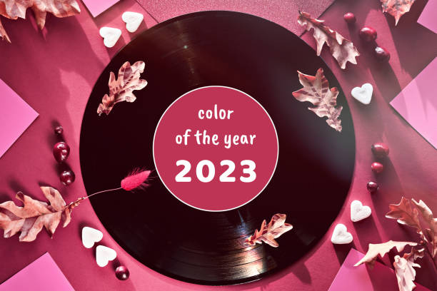 Viva Magenta color of the year 2023. Vintage vinyl records in paper sleeves on black background and paper sleeves. Yellow oak leaves on red background with Autumn decorations. Vintage retro music. stock photo