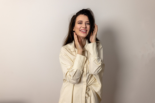 A studio shot of an attractive fashionable woman posing and smiling for the camera.