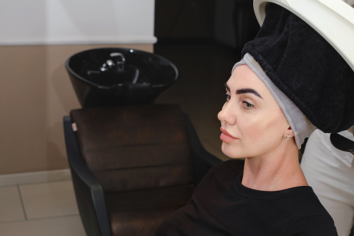 Using steam to dilate the pores of scalp. help to combat hair loss. Scalp cleansing in salon. Woman visiting trichologists for hear professional treatment. Copy space