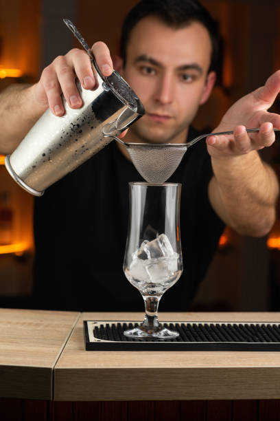 istock Expert barman is making cocktail with shaker at night club. 1446499692