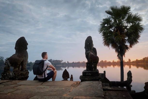 istock Man sitting on steps by lake watching sunrise. 1446500804