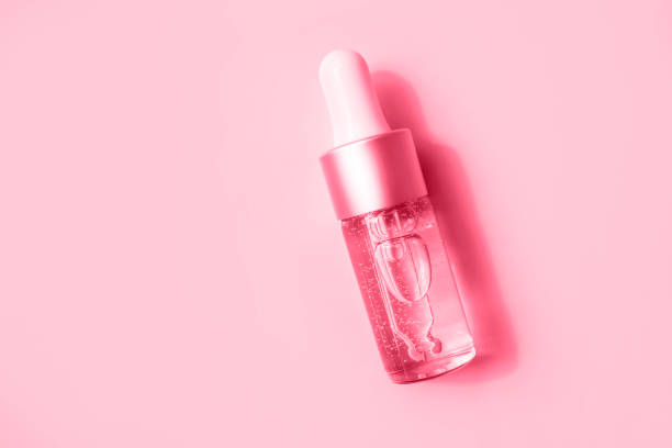 istock A glass dropper bottle with a cosmetic liquid or essence on a background casts a shadow. Flat style and close-up. ?olor Viva Magenta. Demonstrating the colors of 2023. 1446500818