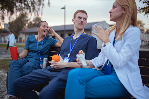 A small group of medical workers sits on a bench in the hospital yard and chats during a coffee break