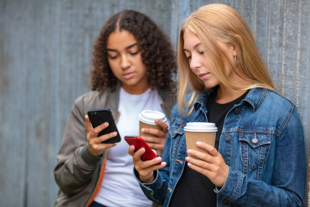 interracial filles métisses adolescentes utilisant des téléphones intelligents buvant du café - red text messaging cafe teenage girls photos et images de collection