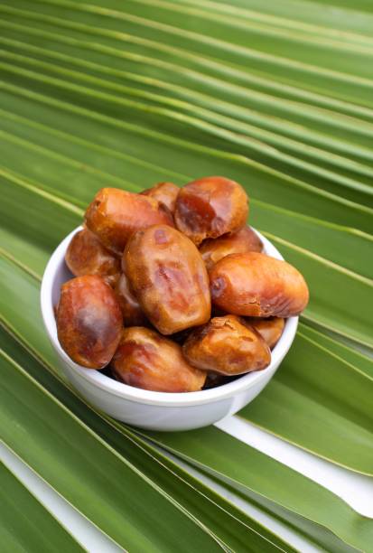 istock Organic Date Palm Fruit or Phoenix Dactylifera in a Bowl Isolated on Palm Leaf in Vertical Orientation 1446504410