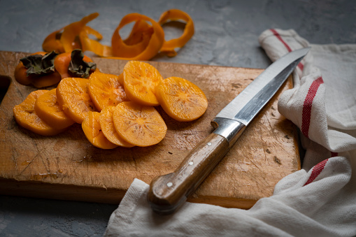 sliced orange persimmons on cutting board