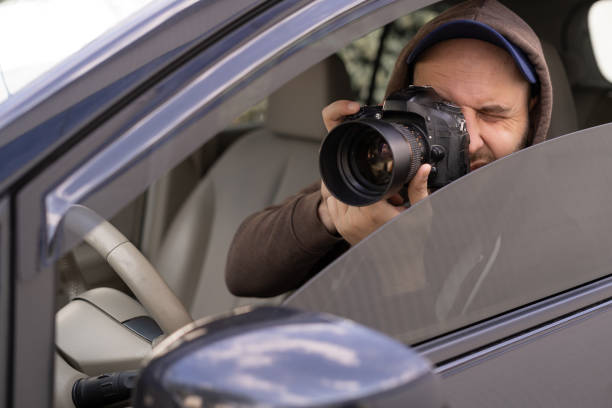istock private detective sitting inside car taking picture with professional slr camera 1446510502
