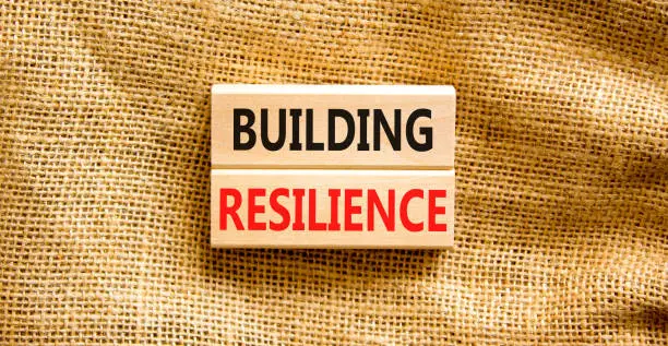 Photo of Building resilience symbol. Concept word Building resilience typed on wooden blocks. Beautiful canvas table canvas background. Business and building resilience concept. Copy space.