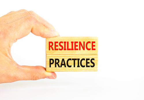 Resilience practices symbol. Concept word Resilience practices typed wooden blocks. Beautiful white table white background. Businessman hand. Business and resilience practices concept. Copy space.