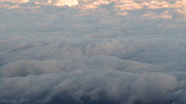 istock White clouds and blue sky with yellow warm sun light from airplane window. 1446513219