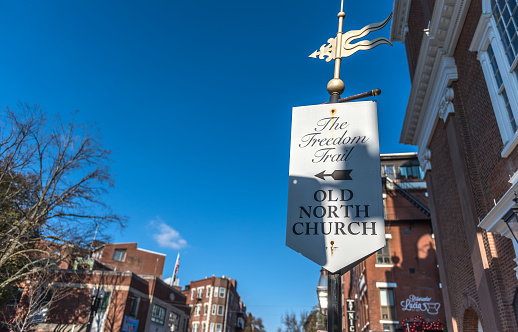 Boston, MA, USA - Nov 23, 2022: Freedom Trail signage on a corner in Boston's North End Italian neighborhood. The North End, Boston’s Little Italy, is a maze of narrow streets with some of the city’s oldest buildings. On the self-guided Freedom Trail, tourists pass historic sites like the 1680 Paul Revere House and the Old North Church, which played a key role at the beginning of the Revolutionary War. Italian restaurants, coffeehouses, pastry shops, and old-school delis pack the area, especially on lively Hanover Street.