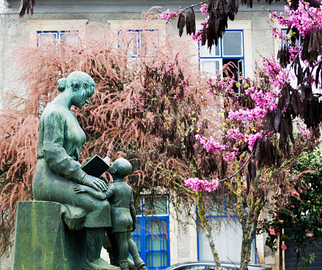 Mirandela, Portugal- April 2, 2011: Town square mother and child statue, Mirandela, Portugal. Flowering bushes.