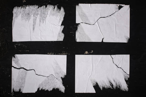 istock Four sheets of white torn paper on a black wall. 1446524031
