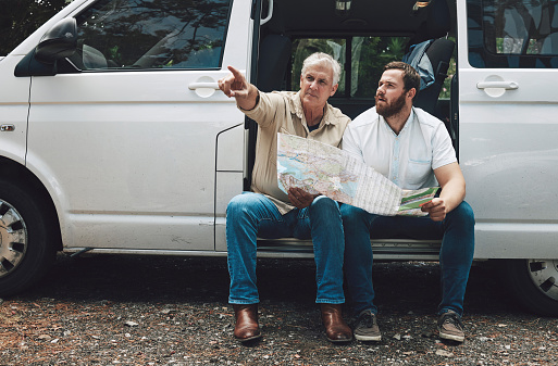 Road trip, map or lost men pointing in travel car, van or moving camper on Australian forest woods street. Traveling, mature father or man thinking of location gps ideas or confused by tourist paper