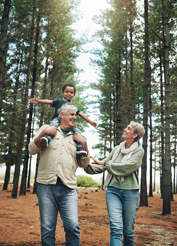 Hike, nature and children with senior foster parents and their adopted son walking on a sand path through the tress. Family, hiking and kids with an elderly man, woman and boy taking a walk outside