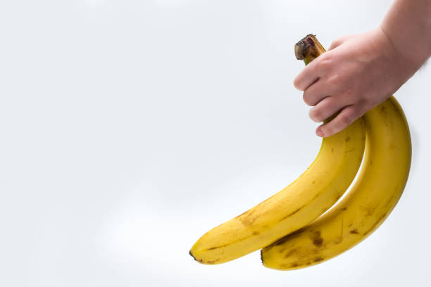 istock The child holds bananas in his hand on a white background. 1446524937