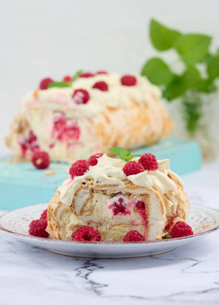 istock Baked meringue roll with cream and fresh red raspberry, white background 1446527381