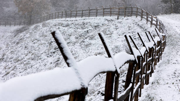 istock Wooden fence covered with a thin layer of the first snow. 1446528236