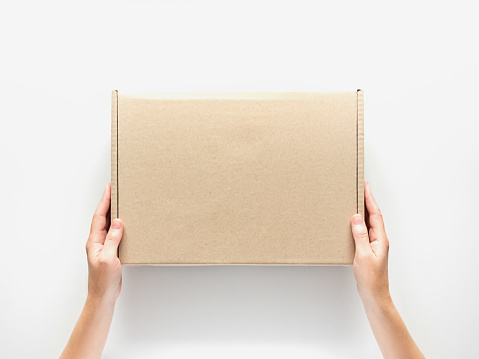 female hands holding a cardboard box on a white background. packaging and delivery concept, top view