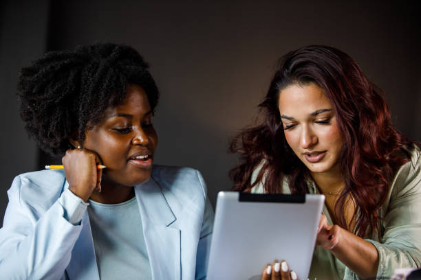 istock Two diverse businesswomen chatting casually while co-working on a project 1446529790