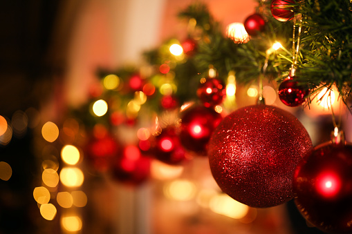 One of four candles is burning for the first Advent on fir branches with Christmas decoration against a grey background, copy space, selected focus, narrow depth of field