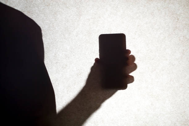 istock The shadow of a guy holding a smartphone. 1446531910