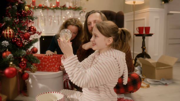 istock Young girl unpacks magic snow globe on Christmas 1446533194