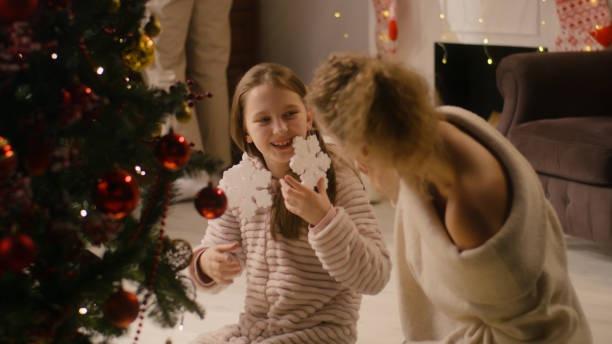 istock Mom having fun with daughter decorating Christmas tree 1446537375