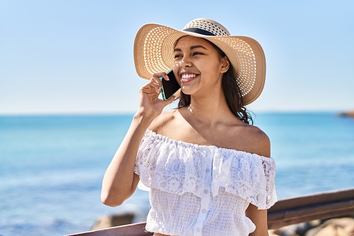Young african american woman tourist smiling confident talking on the smartphone at seaside