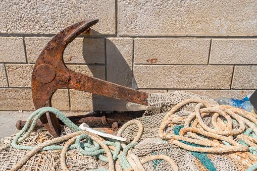 Fishing nets and rusted anchor against stone wall, Croatia