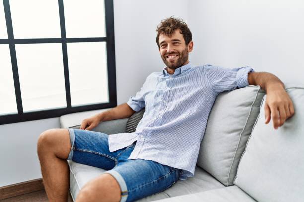 istock Young hispanic man smiling happy sitting on the sofa at home. 1446543026