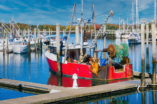 A red fishing trawler is tied to a dock at the Sandwich, Massachusetts marina on a bright November afternoon.