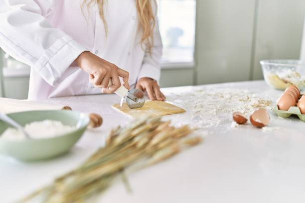 istock Young woman wearing cook uniform cutting pasta dough at kitchen 1446543849