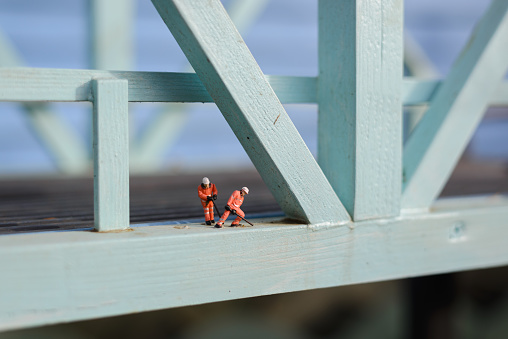 Model toy workers on a blue wooden bridge
