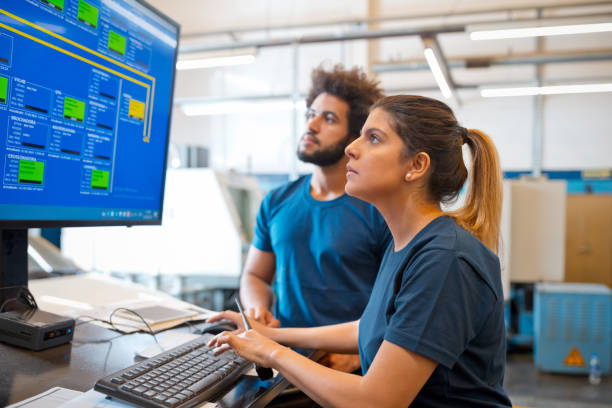 istock Female engineer using computer while standing my male colleague in factory 1446553442