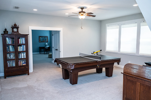 An upstairs loft air used as a bonus game room with a pool table and cabinet.