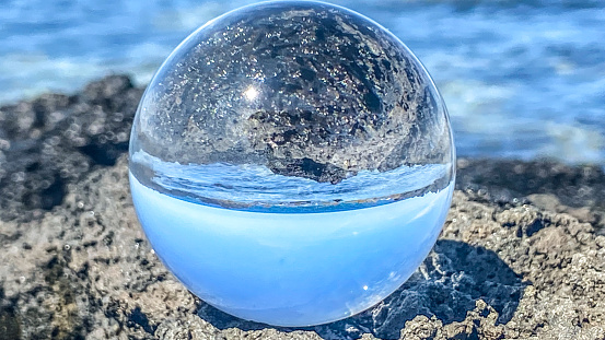 A crystal ball reflects the beauty of Hawaii’s coast. The coral, sand, lava rock and incoming tide create a stunning scene