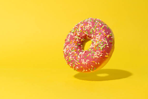 istock Levitating pink donut on yellow background. Creative food background 1446558789