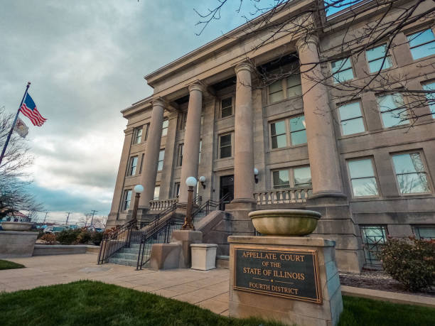 Appellate Court of the State of Illinois District Building Facade in Springfield, Illinois, USA Looking up at the exterior of the Appellate Court of the State of Illinois District Building  in Springfield, Illinois, USA. The American flag and the State of Illinois flag fly at the perimeter of view. The sign for the building is in the forefront of view. Captured on a winter afternoon. springfield illinois skyline stock pictures, royalty-free photos & images