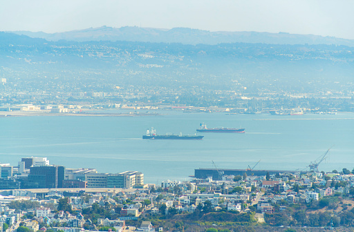 san francisco bay with boats and city and neighborhoods with houses midday in sun with ocean and moutain cloudy background with haze in distance