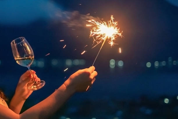 unkenntliche frau mit brennenden wunderkerzen am silvesterabend - sparkler sparks new years eve human hand stock-fotos und bilder