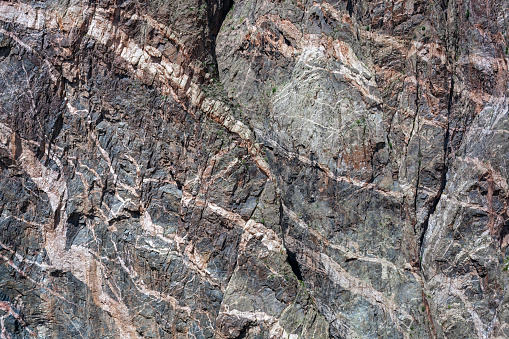 Pale bands of pegmatite in dark gneiss in a massive wall of metamorphic rock in the Black Canyon of the Gunnison.